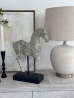 rustic cream horse sculpture on black plyinth stand