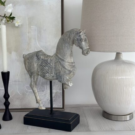rustic cream horse sculpture on black plyinth stand