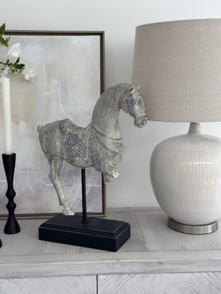 rustic cream horse sculpture on black plyinth stand