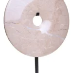 a modern and minimalistic round cream marble disc sculpture on black metal stand