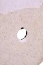 a modern and minimalistic round cream marble disc sculpture on black metal detailed close up