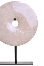 a modern and minimalistic round cream marble disc sculpture on black metal stand front view