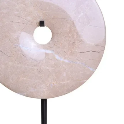 a modern and minimalistic round cream marble disc sculpture on black metal stand front view