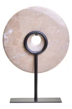 a modern and minimalistic round cream marble disc sculpture on black metal stand rear view