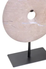 a modern and minimalistic round cream marble disc sculpture on black metal stand up view